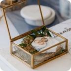 Three gold rings sit in a small glass box.